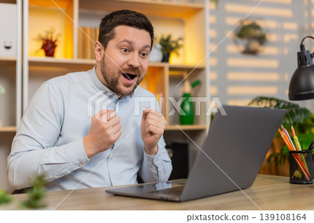 Young man on home table staring at laptop in shock with open mouth after astonishing breaking news Young man on home table staring at laptop in shock with open mouth after astonishing breaking news 139108164