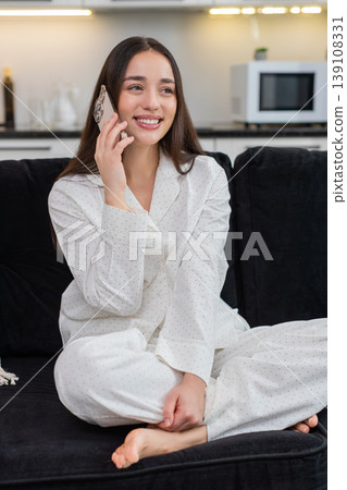 Young woman answers phone cheerful talk active friendly voice smiles laughs shares news lively chat Young woman answers phone cheerful talk active friendly voice smiles laughs shares news lively chat 139108331