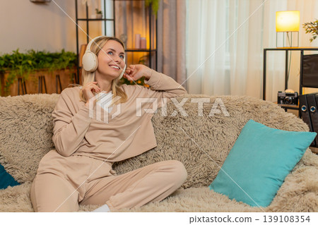 Adult woman listening to music in wireless headphones, moving slowly calm relaxed peaceful rhythm Adult woman listening to music in wireless headphones, moving slowly calm relaxed peaceful rhythm 139108354