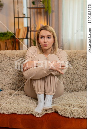 Adult sad woman showing visible stress, tension and emotional irritated, fatigue at home on sofa Adult sad woman showing visible stress, tension and emotional irritated, fatigue at home on sofa 139108376