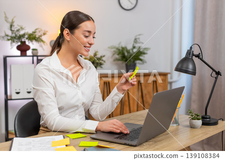 Young businesswoman opens laptop lays stickers and starts first task from list with confident focus Young businesswoman opens laptop lays stickers and starts first task from list with confident focus 139108384