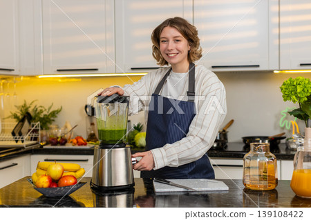 Young woman making green smoothie in home kitchen with blender for healthy diet and fresh meal prep Young woman making green smoothie in home kitchen with blender for healthy diet and fresh meal prep 139108422