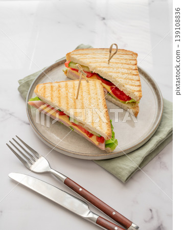 Club sandwich with ham, cheese, tomatoes, lettuce, cucumber on a plate on a white marble background 139108836