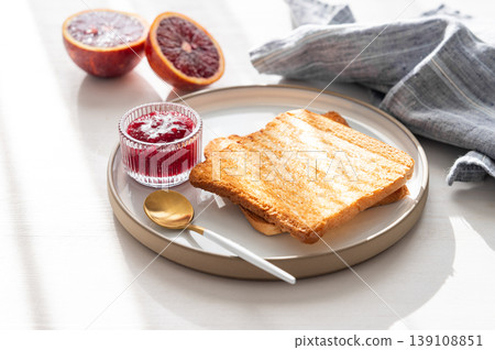 Toast and sweet berry-fruit jam on a plate on a white wooden background with a citrus fruits 139108851