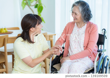 Caregiver supporting a woman in a wheelchair Caregiver supporting a woman in a wheelchair 139109509