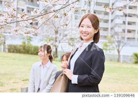 A young woman in a business suit smiles under the cherry blossoms – an image of springtime new beginnings and job hunting. A young woman in a business suit smiles under the cherry blossoms – an image of springtime new beginnings and job hunting. 139109646