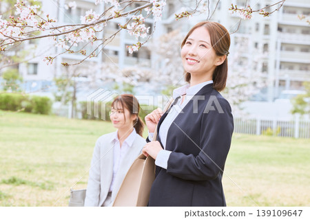 A young woman in a business suit, a new employee, walking under cherry blossoms – an image of spring job hunting. 139109647