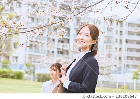 A young woman in a business suit, a new employee, walking under cherry blossoms - an image of a spring company entrance ceremony. A young woman in a business suit, a new employee, walking under cherry blossoms - an image of a spring company entrance ceremony. 139109648