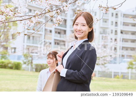 A young woman in a business suit walking under cherry blossoms – an image of spring job hunting. 139109649
