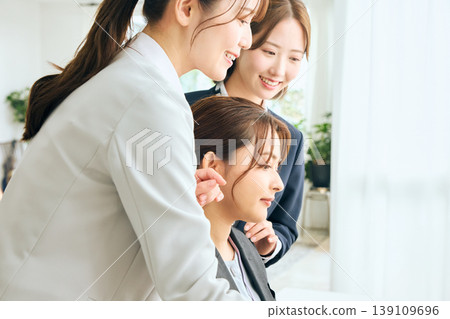 三位年輕的日本女商務人士正在辦公室開會，她們看著電腦螢幕，展現團隊合作精神。 139109696