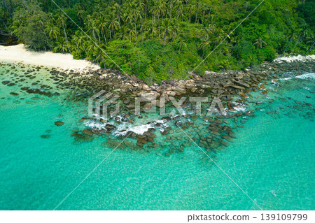Aerial view of a rocky cape and lush green jungle meeting the turquoise ocean. Aerial view of a rocky cape and lush green jungle meeting the turquoise ocean. 139109799