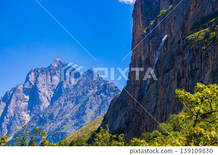 Majestic mountain peaks and waterfall under clear blue sky 139109830