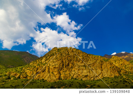 Rocky mountain landscape with green slopes and blue sky 139109848