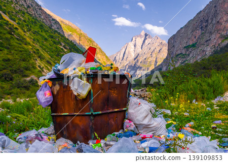 Overflowing trash bin in natural landscape with pollution 139109853