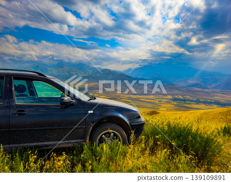 Car on hillside overlooking valley and mountains in Kyrgyzstan under dramatic sky Car on hillside overlooking valley and mountains in Kyrgyzstan under dramatic sky 139109891