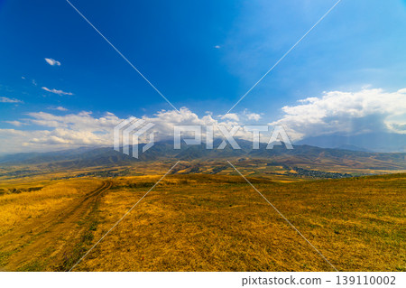 Majestic mountain range with rolling hills and village 139110002
