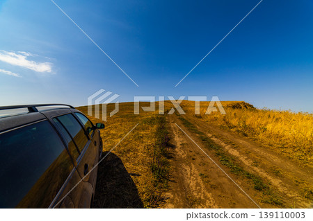 Dark gray station wagon parked on dirt road in rural landscape Dark gray station wagon parked on dirt road in rural landscape 139110003
