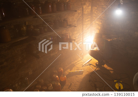 Person adjusting light in dimly lit cellar with preserves Person adjusting light in dimly lit cellar with preserves 139110015
