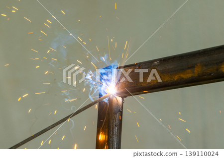 Welding sparks flying from metal beams in industrial setting Welding sparks flying from metal beams in industrial setting 139110024