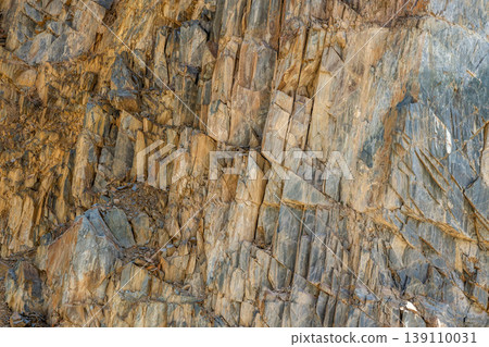 Cracked rock face texture with layered geological formation 139110031