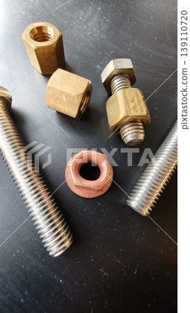 Different types of nuts and bolts on a black surface in a workshop setting Different types of nuts and bolts on a black surface in a workshop setting 139110720