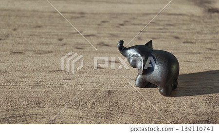Small metal elephant sculpture placed on a wooden surface during daylight Small metal elephant sculpture placed on a wooden surface during daylight 139110741