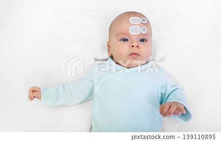 Newborn hearing screening and diagnosis at the hospital. Baby having hearing screening with special electrodes on his head and ear Newborn hearing screening and diagnosis at the hospital. Baby having hearing screening with special electrodes on his head and ear 139110895
