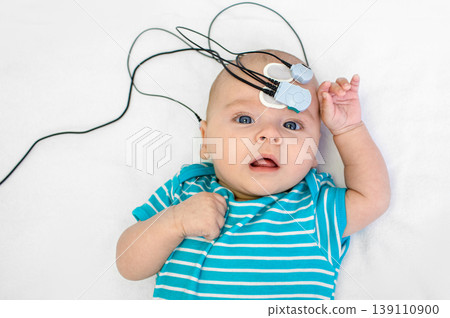 Newborn hearing screening and diagnosis at the hospital. Baby having hearing screening with special electrodes on his head and ear Newborn hearing screening and diagnosis at the hospital. Baby having hearing screening with special electrodes on his head and ear 139110900