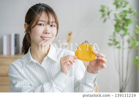 一位女士拿著錢包,裡面裝著存款。 一位女士拿著錢包,裡面裝著存款。 139111219