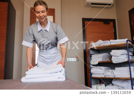 Hotel housekeeper making bed and preparing fresh towels for guests Hotel housekeeper making bed and preparing fresh towels for guests 139111659