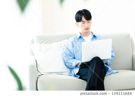 A man who uses a personal computer in the living room A man who uses a personal computer in the living room 139111684