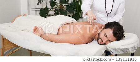Reflexology. Treatment of back pain and tightness with acupuncture needles for a male patient 139111916