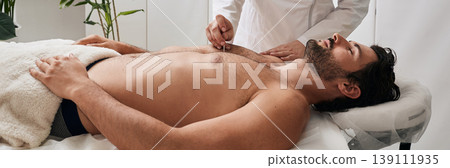 Acupuncture needle in reflexologist hand, near patient chest, during acupuncture procedure at Chinese clinic Acupuncture needle in reflexologist hand, near patient chest, during acupuncture procedure at Chinese clinic 139111935