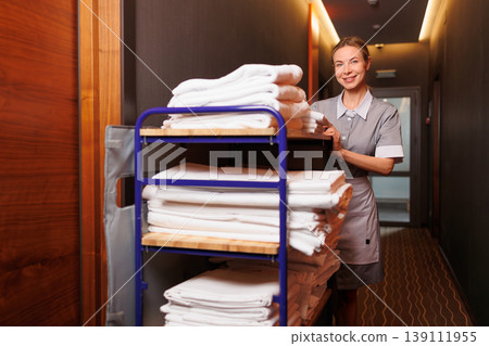 Professional Housekeeper Standing with Linen Cart in Elegant Hotel Corridor Professional Housekeeper Standing with Linen Cart in Elegant Hotel Corridor 139111955
