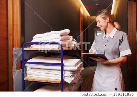 Hotel Housekeeping Staff Checking Inventory on Linen Cart with Clipboard Hotel Housekeeping Staff Checking Inventory on Linen Cart with Clipboard 139111956