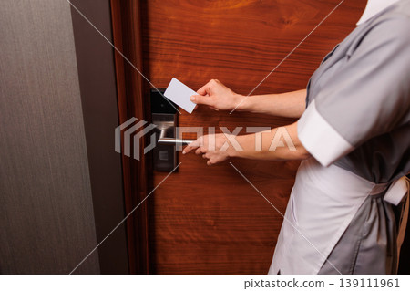 Housekeeping staff using keycard to unlock hotel room door close detail Housekeeping staff using keycard to unlock hotel room door close detail 139111961