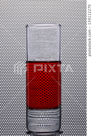 A shot glass with a red drink against a background with round holes A shot glass with a red drink against a background with round holes 139112270