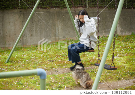 A young girl playing with a cute Pomeranian puppy in the park of her apartment complex in spring. A young girl playing with a cute Pomeranian puppy in the park of her apartment complex in spring. 139112991