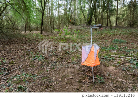 Orienteering control point with orange and white flag 139113216