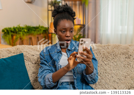 African American sad amazed woman reacts with shock while reading unexpected news on smartphone 139113326