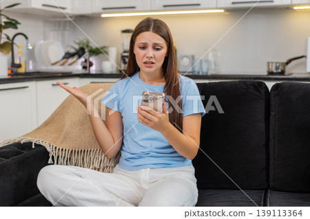 Young woman sees negative alert on smartphone frowns worried says why happened stressed and upset in Young woman sees negative alert on smartphone frowns worried says why happened stressed and upset in 139113364