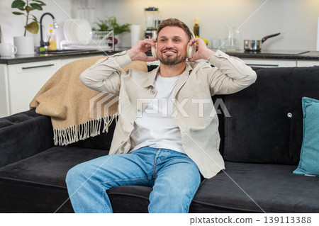 Young man enjoys playlist on wireless headphones relax mood eyes closed gentle smile meditative calm Young man enjoys playlist on wireless headphones relax mood eyes closed gentle smile meditative calm 139113388