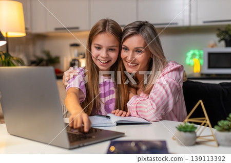 Mother and daughter send homework online on laptop child presses submit mother smiles closes laptop 139113392