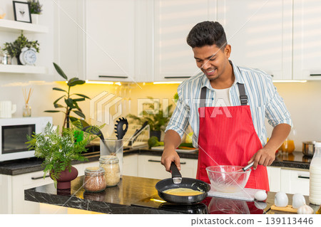 Indian man pouring egg mixture into frying pan for healthy omelet breakfast meal in modern kitchen Indian man pouring egg mixture into frying pan for healthy omelet breakfast meal in modern kitchen 139113446