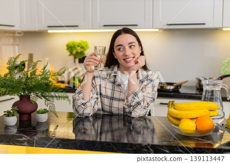 Young woman drinks filtered water in kitchen, healthy habit hydration routine and wellness lifestyle Young woman drinks filtered water in kitchen, healthy habit hydration routine and wellness lifestyle 139113447