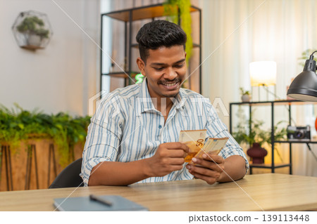 Indian man counts euro cash after salary bonus invests smiles proud about profit wealth and success Indian man counts euro cash after salary bonus invests smiles proud about profit wealth and success 139113448