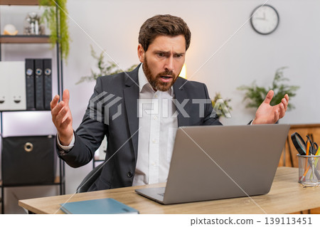 Middle-aged businessman sees laptop freeze eyes widen press key reboots system upset data loss after 139113451