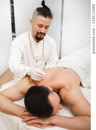Osteochondrosis treatment with acupuncture. Certified reflexologist treats man back in spa 139113468