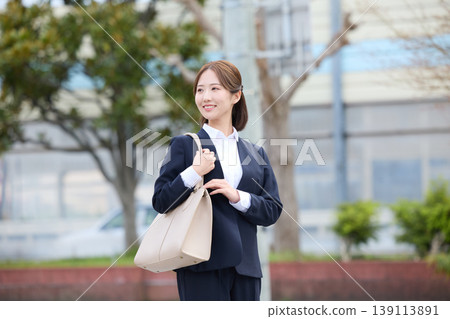 春天，年輕的職業婦女穿著職業套裝走在城市街道上；她們穿著招募服，正在尋找工作。 139113891