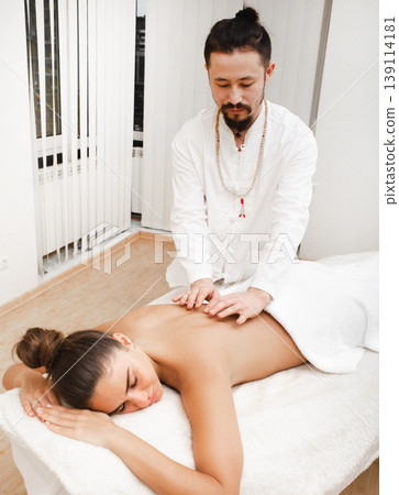 Doctor asian race doing energetic body massage. Woman getting reiki therapy. Alternative medicine Doctor asian race doing energetic body massage. Woman getting reiki therapy. Alternative medicine 139114181